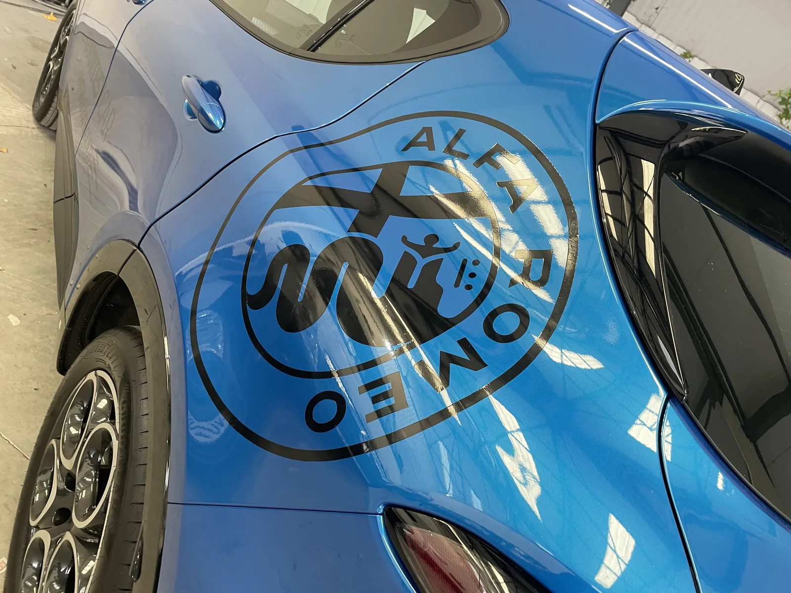 Large circular cut-vinyl decal applied over the curved rear bodywork of a blue car