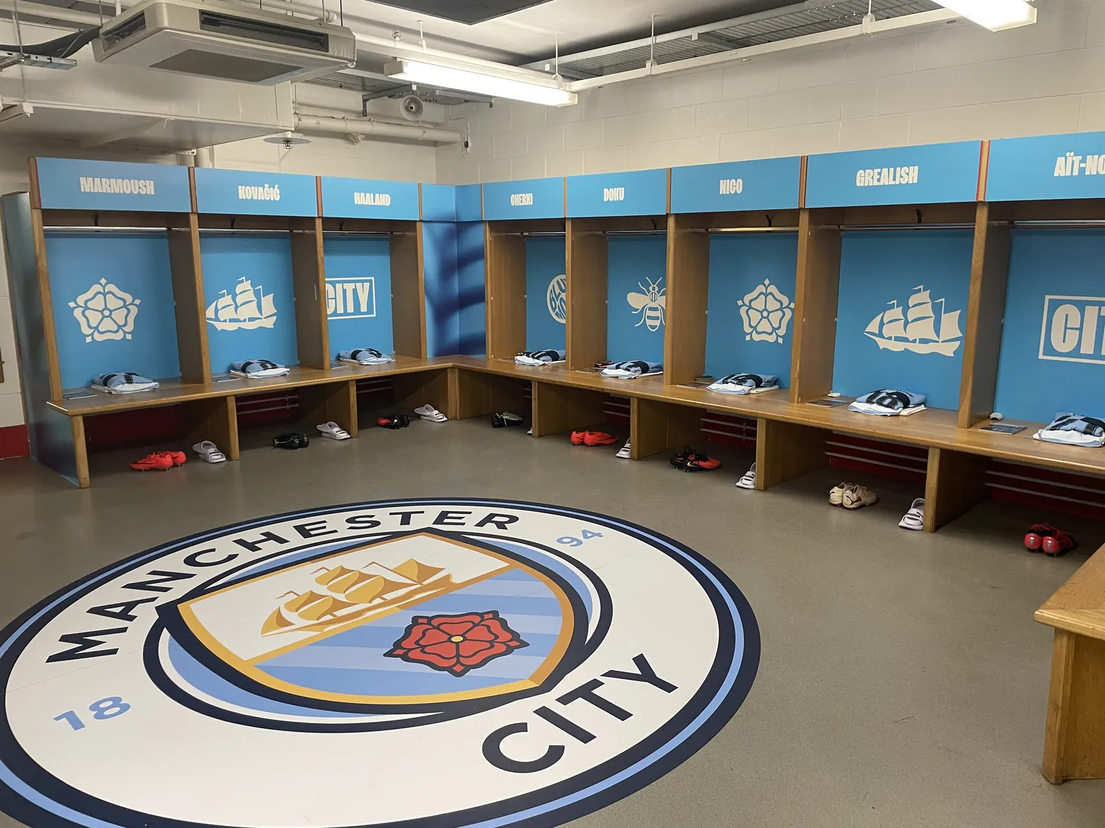 Printed locker panels above the benches and a large circular crest graphic on the dressing room floor